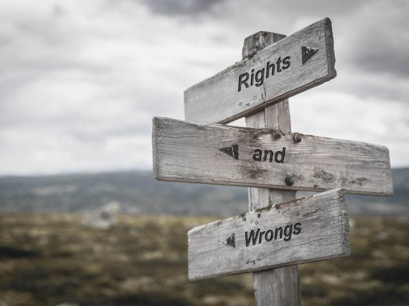 rights and wrongs text on wooden sign outdoors.